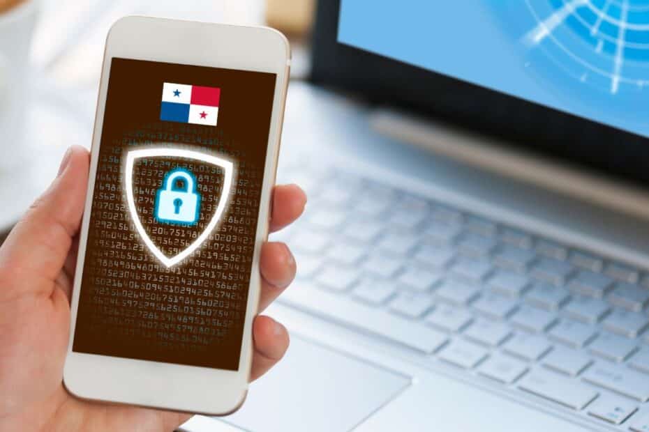 Cybersecurity shield on a phone in front of a laptop