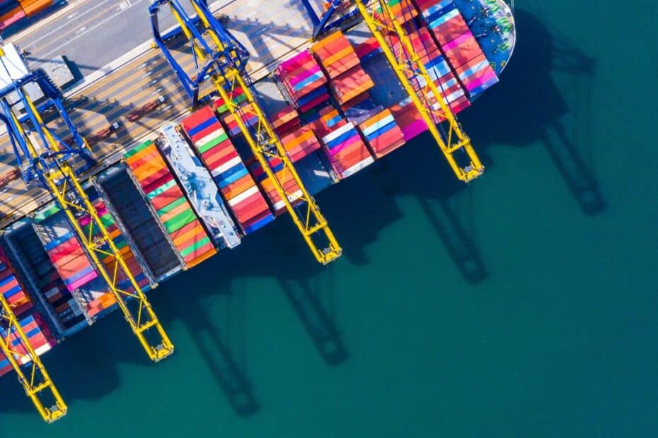 Container ship under crane docked at port terminal